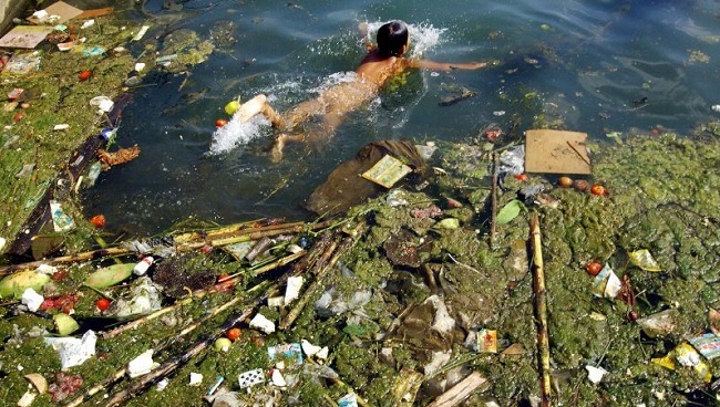 Enfant qui nage dans la rivière polluée de Chine